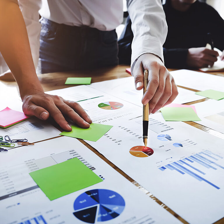 Young business woman holding a pen pointing the graph and partnership to analyze the marketing plan with calculator on wood desk in office_